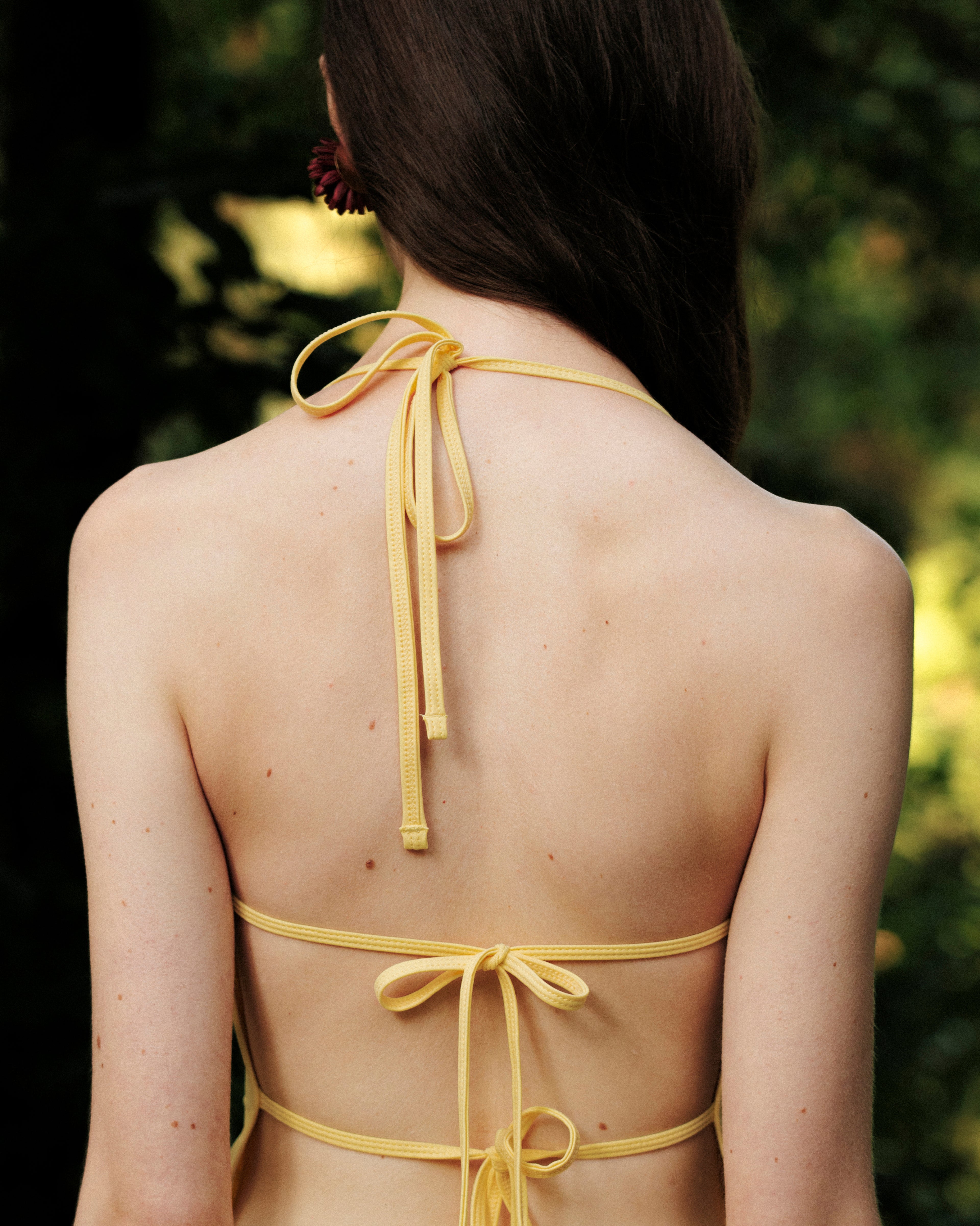Back view of woman wearing yellow tankini with ties